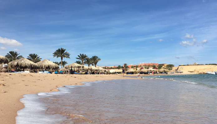 En bild på en strand där vågorna slår upp mot land.