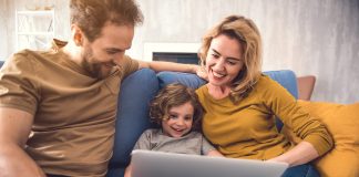 Eltern und Kind sitzen vor einem Laptop und buchen online eine Reise