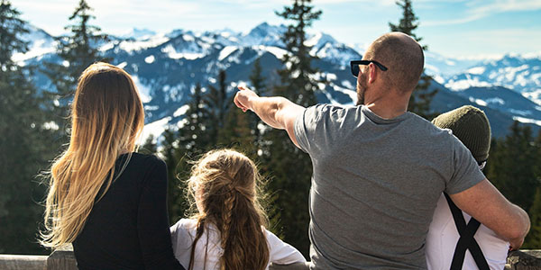 Familj som tittar ut över snötäckta berg.