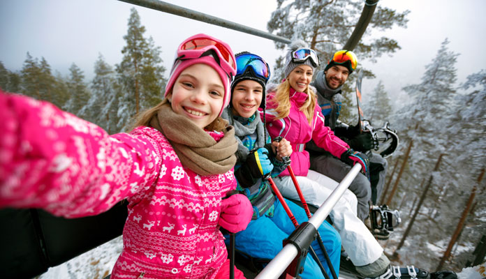 Skidresa familj Schweiz, en familj sitter i en skidlift.