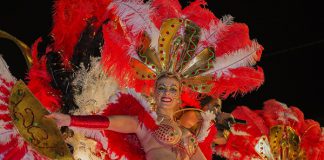 Carnaval in de zon op Madeira Sierlijk verklede vrouw met rode en witte veren.