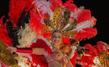 Carnaval in de zon op Madeira Sierlijk verklede vrouw met rode en witte veren.