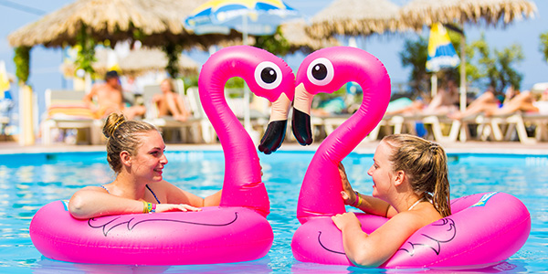 Twee meiden in het zwembad in opblaasbare flamingo's.