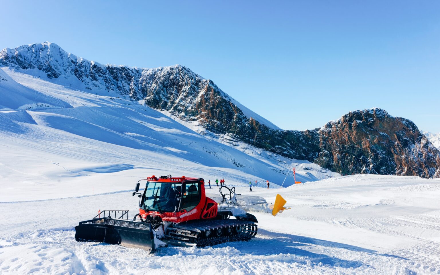 Eine Pistenraupe bei der Instandhaltung des Hintertuxer Gletschers in Österreich an einem sonnigen Tag.