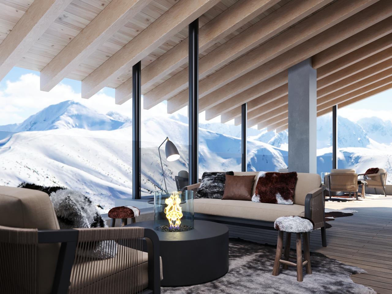 Interieur eines Hotels mit Couch, Stühlen, Decken und Kissen. Große Fenster mit dahinter einer verschneiten Winterlandschaft.