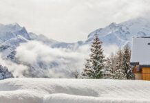 Winterlandschaft mit verschneitem Chalet und Bergen.