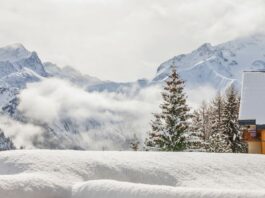 Winterlandschaft mit verschneitem Chalet und Bergen.