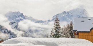 Winterlandschaft mit verschneitem Chalet und Bergen.