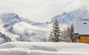 Winterlandschaft mit verschneitem Chalet und Bergen.