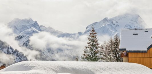 Winterlandschaft mit verschneitem Chalet und Bergen.