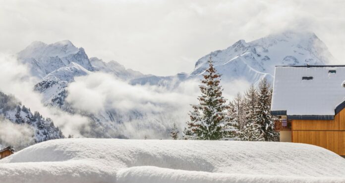 Winterlandschaft mit verschneitem Chalet und Bergen.